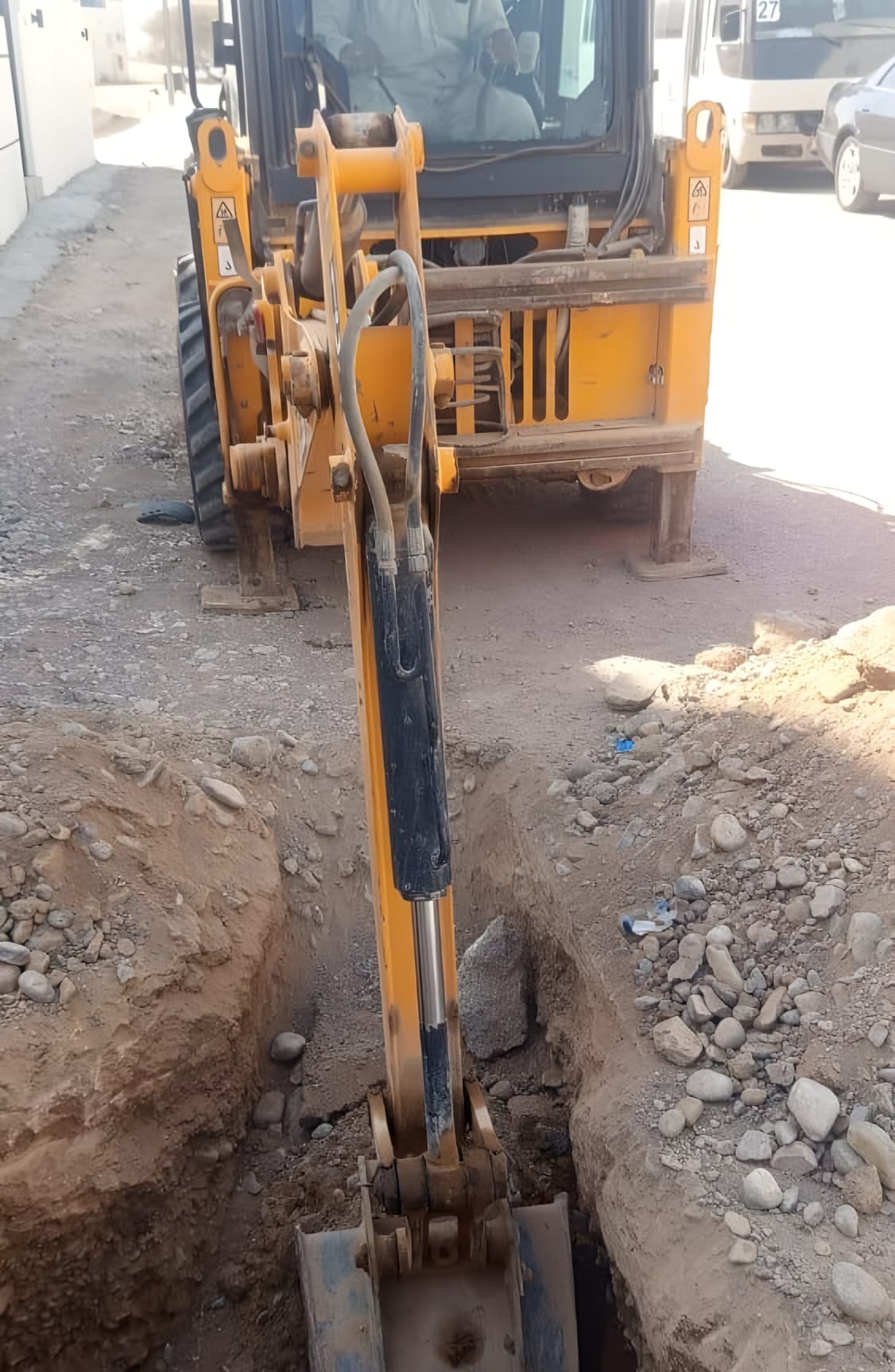 Backhoe cutting a service trench in a residential street